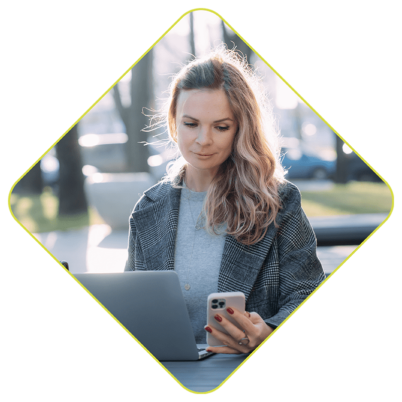 Woman checking phone and working with laptop